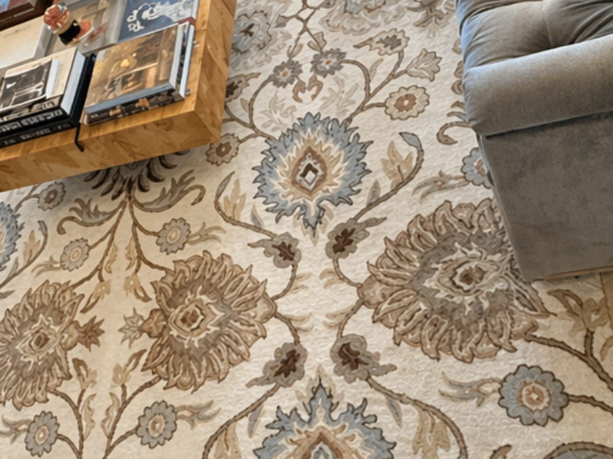 Cream floral area rug freshly cleaned under the coffee table, with the sofa still in place beside it